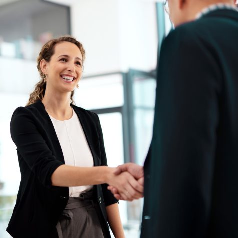 Two business people shaking hands in office - Close up